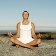 Man Meditating on a Rock at the Beach --- Image by © Royalty-Free/Corbis