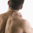 Man Rubbing His Shoulder Muscle